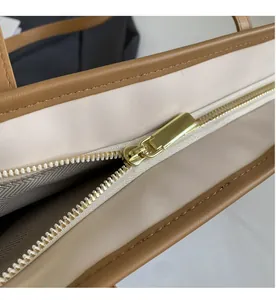 Detailed close-up of smooth gold zipper and premium stitching on tote bag's leather trim