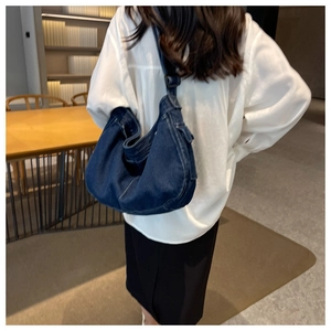 Detail of dark blue denim hobo bag with cargo pocket shown worn on a shoulder