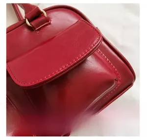 Detail shot of wine red faux leather texture and stitching on trendy small square bag