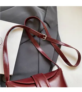 Detail of burgundy leather bucket bag featuring a smooth adjustable shoulder strap