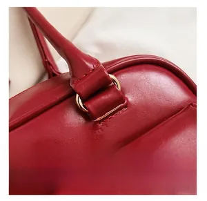 Close-up of golden D-ring hardware and precise stitching on red leather handbag