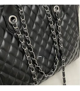 Close-up of black quilted leather texture and silver chain strap on a tote bag