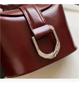 Close-up of wine red bucket bag showing silver D-ring buckle and reinforced stitching