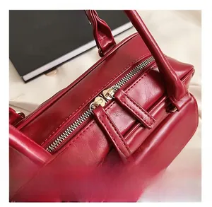Close-up of smooth metal zipper and premium leather texture on a red handbag