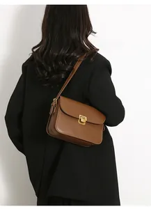 Detail of a brown leather shoulder bag with a vintage flap and square gold metal lock buckle