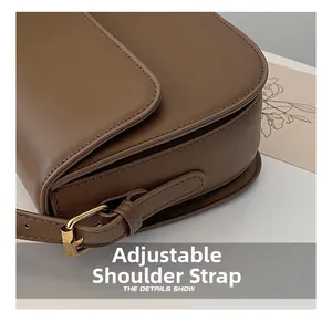 Détail de la bandoulière réglable en cuir marron avec boucle dorée sur le sac à main