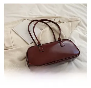 Detail view of burgundy faux leather baguette bag with thin straps and silver hardware