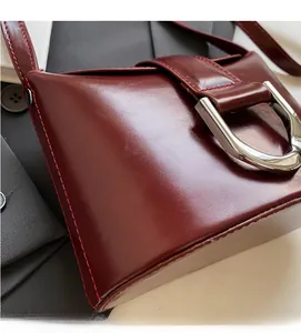 Close-up of wine red leather bucket bag with silver D-ring buckle and red stitching details