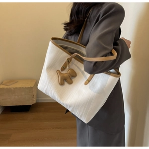 Detail of white tote bag with wave texture, brown trim and cute puppy charm accessory