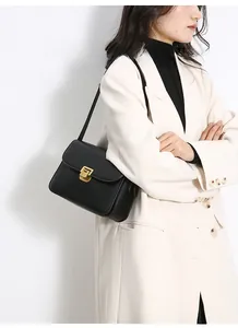 Detail of a black vintage square bag featuring a gold metal buckle on a beige blazer