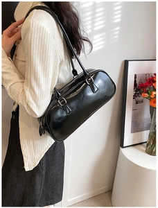 Polished black Boston bag detail showing slim shoulder straps and silver metal hardware