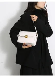 Detail of white rectangle shoulder bag with gold square clasp on black suit model