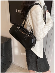 Detailed side view of black glossy leather Boston bag with dual handles on model