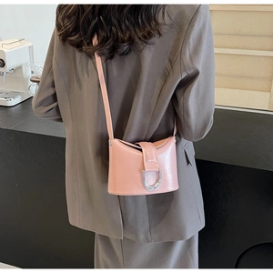 Pink semi-circle crossbody bag with silver buckle worn by a model in a grey suit