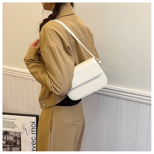 Vue latérale d'une femme portant un sac sous le bras en cuir blanc avec bandoulière