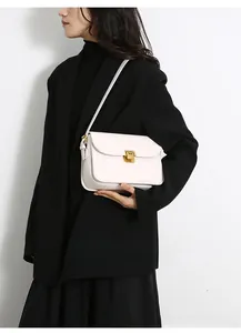 Detailed view of a cream leather crossbody bag with a vintage gold metal buckle closure