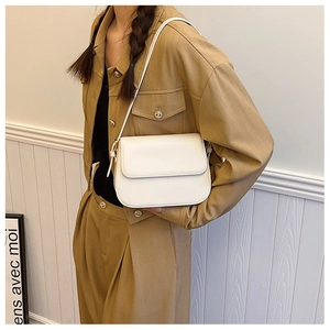 Vue latérale d'un sac sous le bras en cuir blanc crème porté avec un blazer kaki élégant