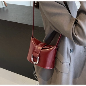 Close-up of a burgundy leather bucket bag with a silver U-shaped metal buckle detail