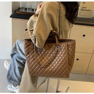Detailed view of quilted stitching and gold chain strap on a large brown tote bag