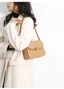 Detail of khaki leather crossbody bag with metal square buckle worn with a beige blazer