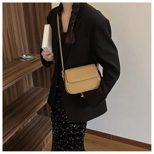 Détail d'un petit sac bandoulière marron en similicuir porté dans une bibliothèque
