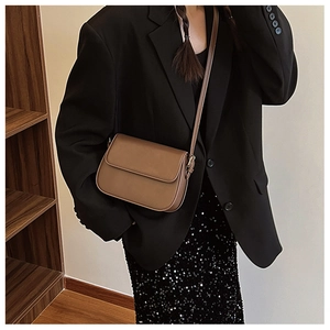 Détail d'un sac à bandoulière marron porté avec un blazer noir pour un look élégant