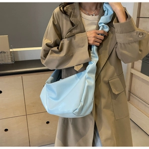 Detailed view of light blue pleated tote bag on shoulder with khaki trench coat styling