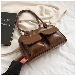 Detailed close-up of brown leather handbag with dual front pockets and sleek matte finish