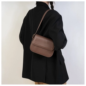 Sac bandoulière en cuir marron porté à l'épaule pour montrer la taille et le style