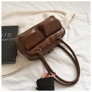 Detail of dark brown retro PU leather handbag with two front pockets and long handles