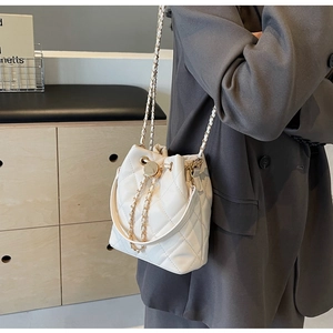 Dettaglio di una borsa a secchiello trapuntata bianca con catena dorata su modella