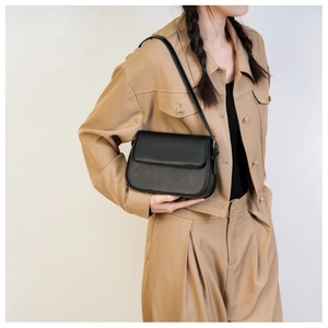 Sac à bandoulière minimaliste en similicuir noir avec rabat porté par un mannequin