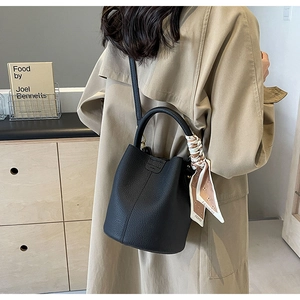 Detail of black pebbled leather bucket bag with fashion silk scarf on model