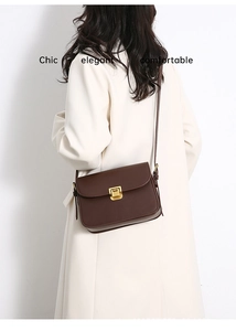 Detail view of a dark brown leather flap bag with a golden square twist lock on a model