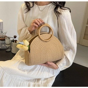 Détail d'un sac à main demi-lune en paille tressée avec poignées rondes et tulipes déco