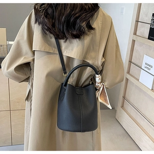 Detailed view of black pebble leather bucket bag with decorative silk scarf on handle
