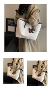 Macro detail of white textured tote bag with contrast brown straps and dog charm