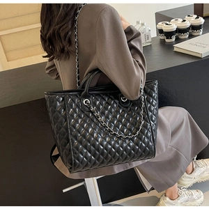 Quilted tote bag with leather chain strap shown in a cozy cafe setting during commute