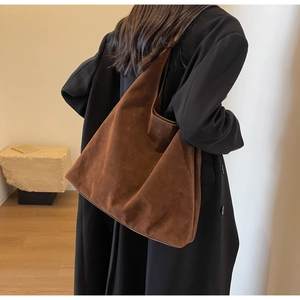 Brown suede tote bag side view on shoulder showing soft texture and large capacity