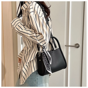 Détail du sac à main noir texture lychee avec foulard en soie imprimé et finitions dorées