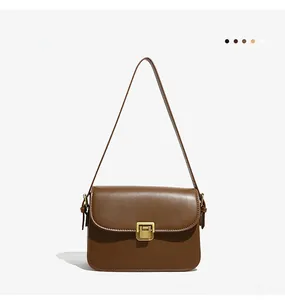Detail view of the vintage gold push-lock closure on a classic brown square shoulder bag