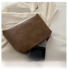 Petite pochette rétro en similicuir marron montrant sa capacité pour un smartphone
