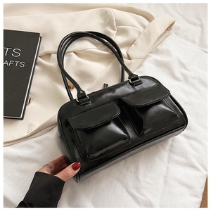 Detail view of glossy black faux leather shoulder bag featuring dual front utility pockets