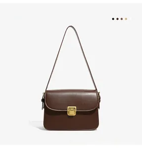 Close-up of coffee brown leather crossbody bag with vintage gold square metal clasp