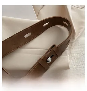 Détail de la bandoulière réglable en daim marron avec boucle argentée et rivets