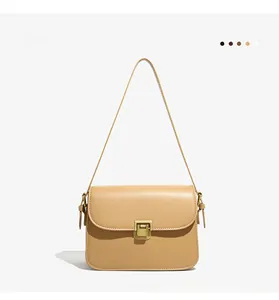 Detailed view of yellow crossbody bag with vintage gold metal lock and leather strap