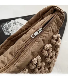 Detailed macro view of the smooth silver zipper on a brown quilted flower tote bag