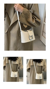 Detailed close-up of cream leather bucket bag with a large silver horseshoe buckle