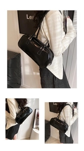 Detail view of a black glossy leather baguette bag featuring parallel shoulder straps