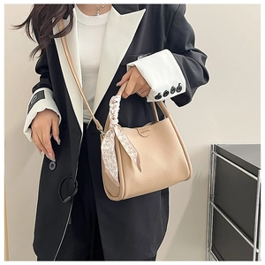Détail du sac seau abricot en cuir grainé avec foulard en soie à motif cœur sur l'anse
